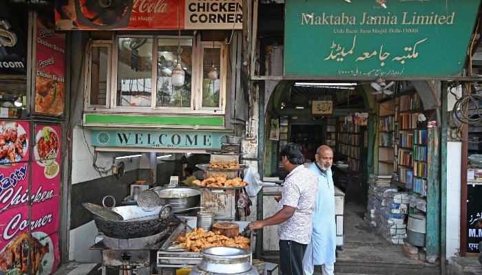 A shop owner (right) standing outside his Urdu literature bookshop at Urdu Bazar in the old quarters of Delhi on October 14, 2024. —AFP