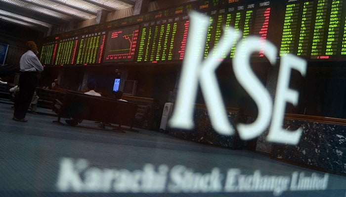 Pakistani stockbrokers watch the latest share prices on a digital board during a trading session at the PSX in Karachi on May 28, 2013. — AFP