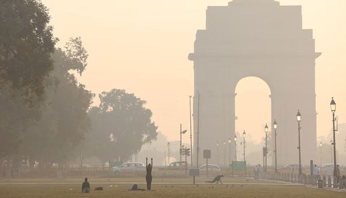 People exercise on a grass lawn near India Gate along Kartavya Path on a smoggy morning in New Delhi, India. — Reuters