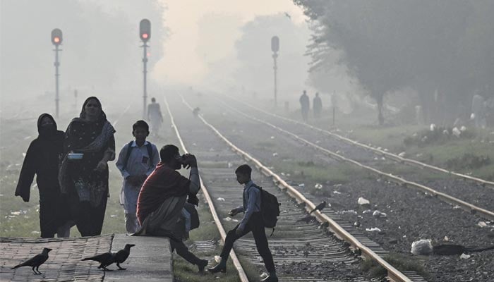 A school boy cross a railway track amid smoggy conditions in Lahore on November 4, 2024. — AFP