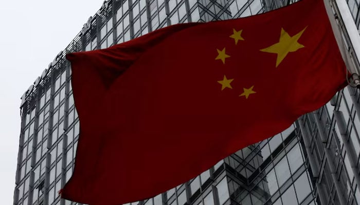 A building housing the PricewaterhouseCoopers (PWC) branch office stands behind a Chinese national flag in Beijing January 24, 2014. — Reuters