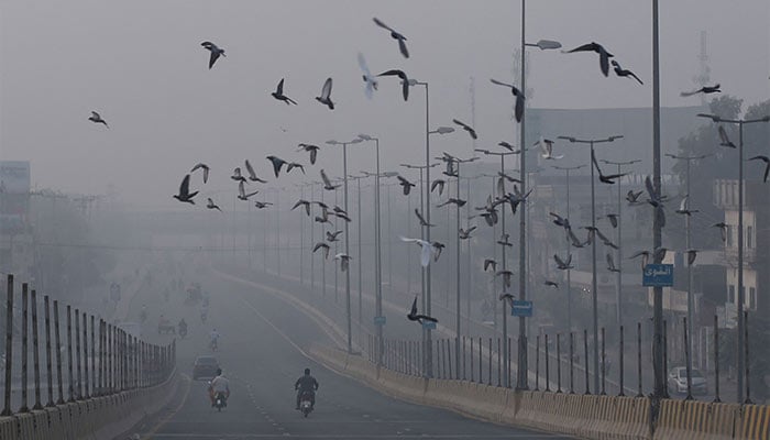 Commuters ride along a highway engulfed in smog in Multan on November 7, 2024. — AFP