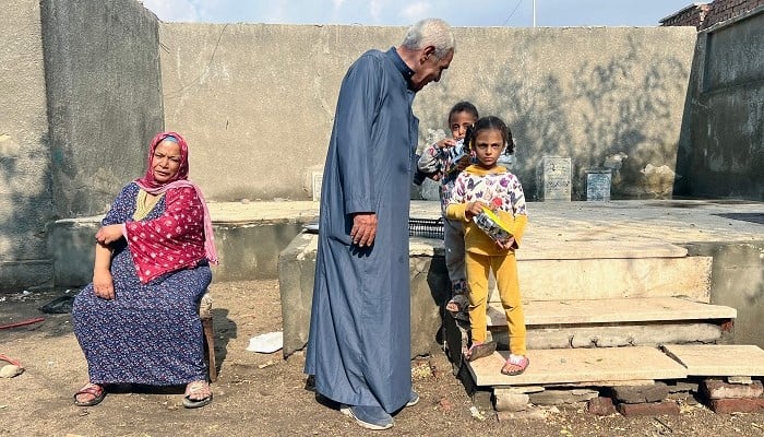 Sayyed al-Arabi, 71, who has lived and guarded the Ain Al-Sira cemetery in Old Cairo, for decades, speak to his granddaughters on November 4, 2024. — AFP