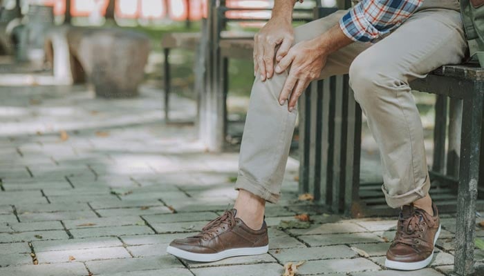 A rperesentational image shows a man holding onto his knee. — Unsplash