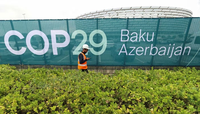 A worker walks along a fence near the Baku Olympic Stadium, the venue of the COP29 United Nations Climate Change Conference, in Baku, Azerbaijan, October 18, 2024. — Reuters