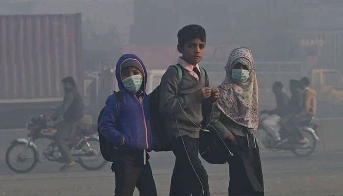 Children walk to school amid heavy smog conditions in Lahore. — AFP/File