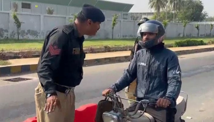 Police personnel stop commuters at a checkpoint on a road leading towards Karachi airport, on November 13, 2024. — Reporter