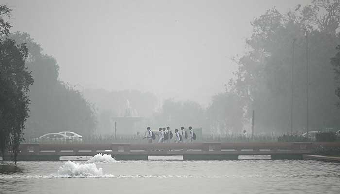 Children walk near India Gate engulfed in smog in New Delhi on November 13, 2024. —AFP