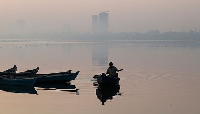 A fisherman is silhouetted as he rows a boat amid smog and air pollution on a morning in Karachi, Pakistan, November 14, 2024. — Reuters