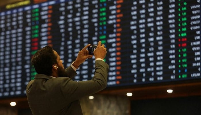 A man takes a photo of the electronic board at the Pakistan Stock Exchange, in Karachi November 28, 2023. — Reuters