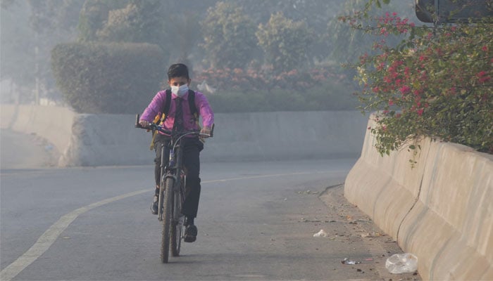 Student rides a bicycle to school amid dense smog in Lahore, on November 24, 2021. — Reuters