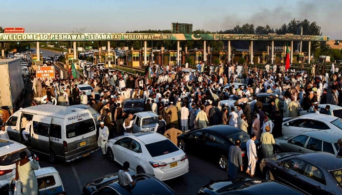 PTI supporters holding a protest on a main artery in Peshawar on October 21, 2022. — AFP