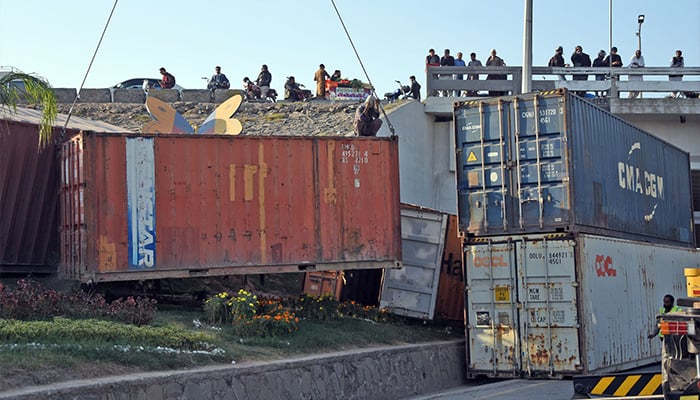 Workers busy placing heavy shipping containers near Faizabad flyover along Islamabad Highway for road block ahead of PTI protest in Islamabad — November 21, 2024. — Online