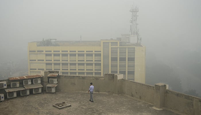 A man uses his mobile phone as he walks on the roof of a building amid smog air pollution in Lahore, Pakistan November 14, 2024. — Reuters