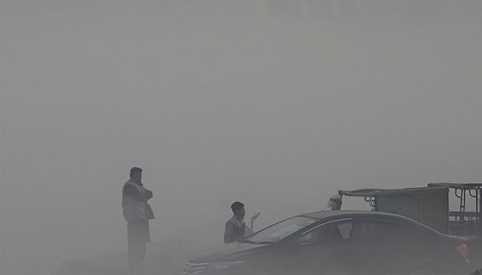 People gathered at a wholesale fish market engulfed in smog in Lahore on November 21, 2024. — AFP