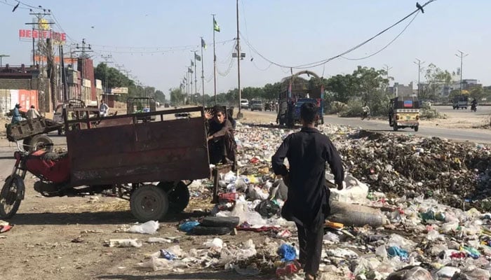 A minor waste picker sits next to a roadside garbage heap near Al-Asif Square, Karachi on November 11, 2023. — Reuters