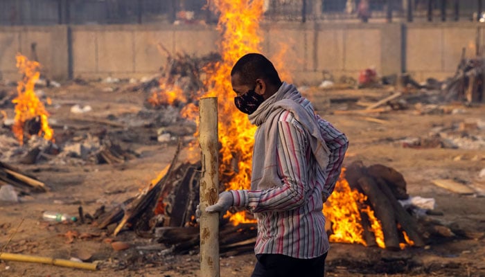 A man walks past burning funeral pyres of people, who died due to the coronavirus, at a crematorium ground in New Delhi, India, April 22, 2021. — Reuters