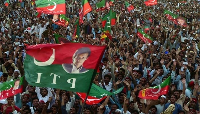 PTI supporters wave party flags during a rally in Charsadda. — AFP/File