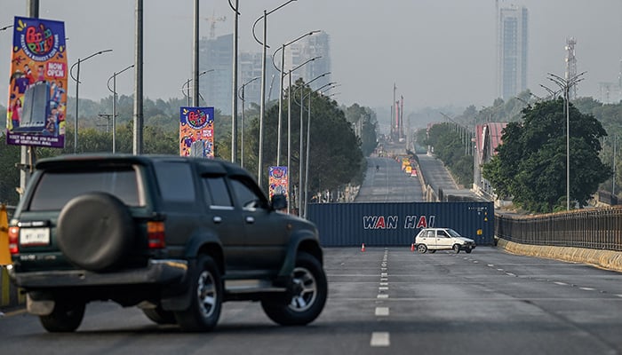 Vehicles return back on a road blocked with shipping containers near the Red Zone area ahead of a protest rally by jailed former prime minister Imran Khans Pakistan Tehreek-e-Insaf (PTI) party in Islamabad on November 24, 2024. — AFP