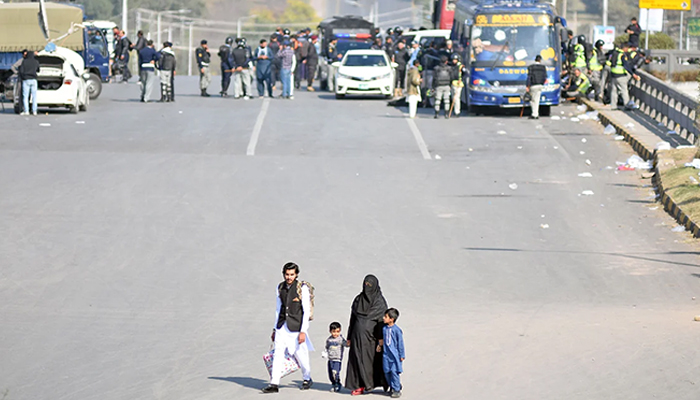 Family walks on Faizabad Bridge on the way during roads blocked and markets closed in the twin city ahead of PTI protest in Islamabad on November 25, 2024. — Online