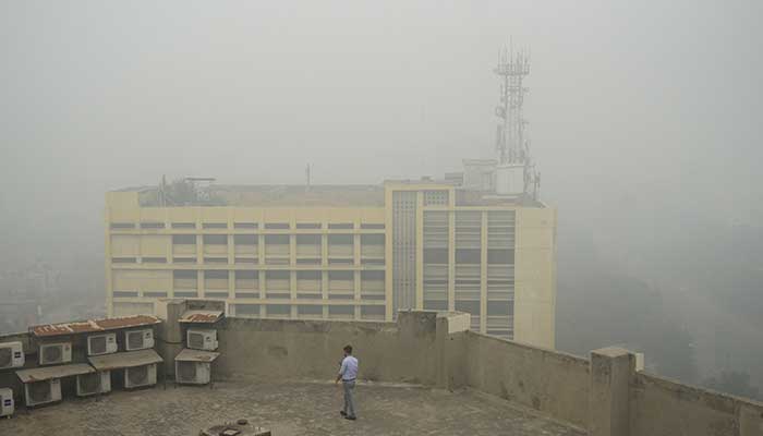 A man uses his mobile phone as he walks on the roof of a building amid smog air pollution in Lahore, November 14, 2024. — Reuters