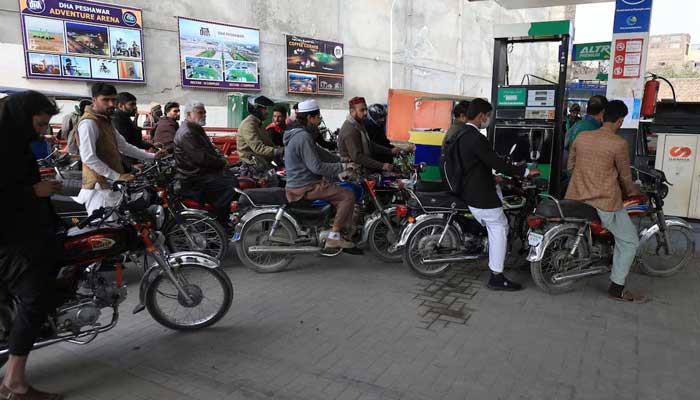 People wait for their turn to get fuel at a petrol station. — Reuters/File