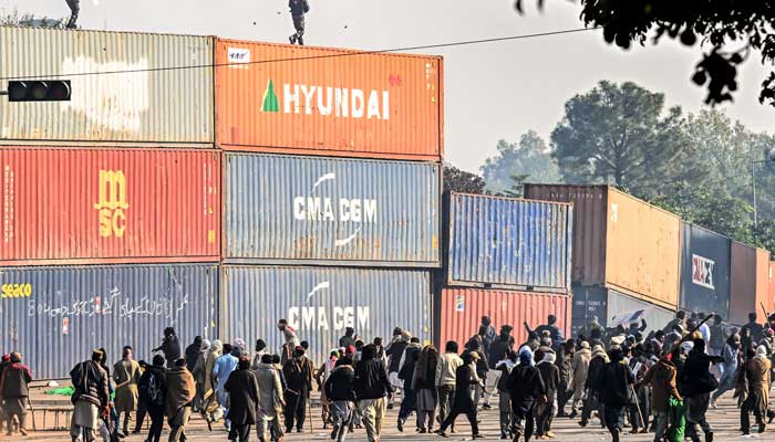 PTI supporters throw stones at paramilitary soldiers on top of the shipping containers during a protest at the Red Zone area in Islamabad on November 26, 2024. — AFP