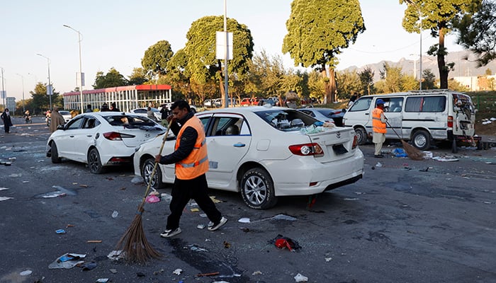 Workers clear the road near damaged vehicles, after security forces launched a raid on supporters of former prime minister Imran Khans PTI who had stormed the capital demanding his release on Tuesday, in Islamabad, November 27, 2024. — Reuters