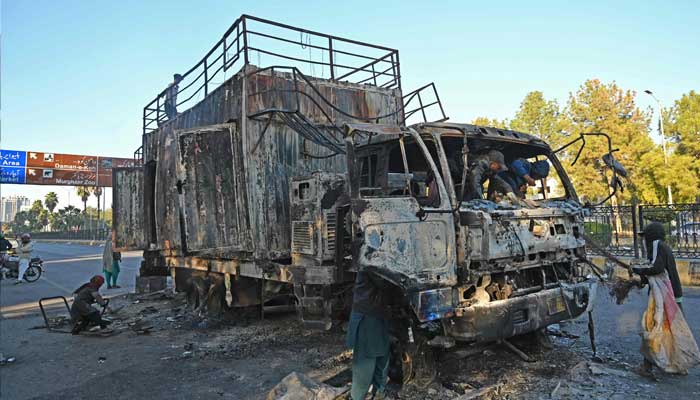 Ragpickers collect scraps from a burnout rally truck used by Bushra Bibi, the wife of PTI founderImran Khan, near the Red Zone in Islamabad on November 27, 2024. — AFP