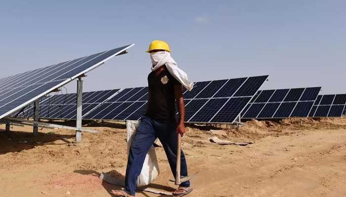 An engineer walks past solar panels in the western state of Rajasthan, India. — AFP/File