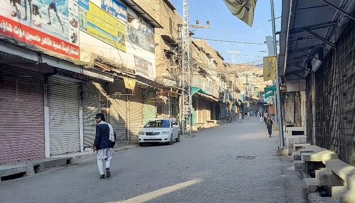 Men walk past a market closed by traders during a strike in District Kurram, KP, on November 22, 2024. — AFP