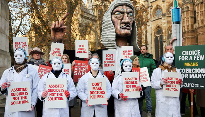 Protestors hold placards as they gather outside the Parliament as British lawmakers debate the assisted dying law, in London, Britain, November 29, 2024. — Reuters