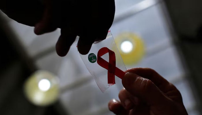 An representational image shows a nurse (L) handing out a red ribbon to a woman, to mark World Aids Day, at the entrance of Emilio Ribas Hospital, in Sao Paulo on December 1, 2014. — Reuters