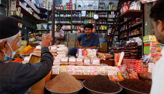 A shopkeeper listens to a customer as he sells groceries at a shop in a market in Karachi, Pakistan June 10, 2022. — Reuters