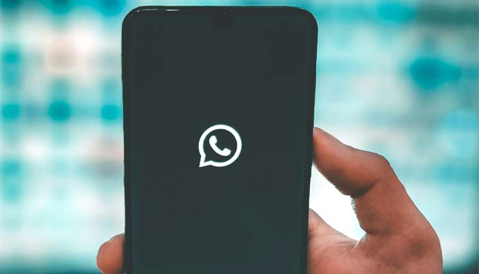 A representational image shows the WhatsApp logo displayed on a phone screen. — Unsplash