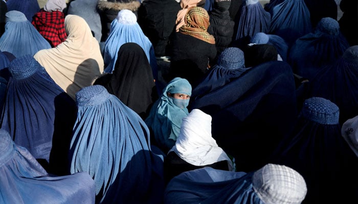 A girl sits in front of a bakery in the crowd with Afghan women waiting to receive bread in Kabul, Afghanistan, January 31, 2022. — Reuters