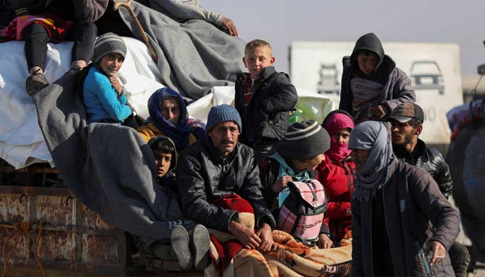 Displaced people who fled from Aleppo countryside, sit together on the back of a truck in Tabqa, Syria December 3, 2024. — Reuters