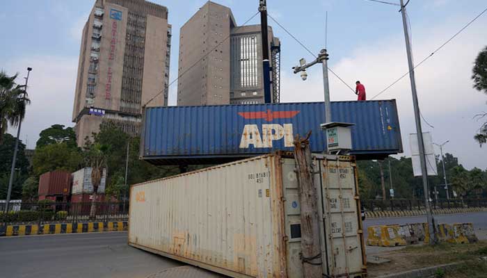 A worker places shipping containers to close a road ahead of a planned rally by PTI supporters in Islamabad on November 23, 2024. — AFP