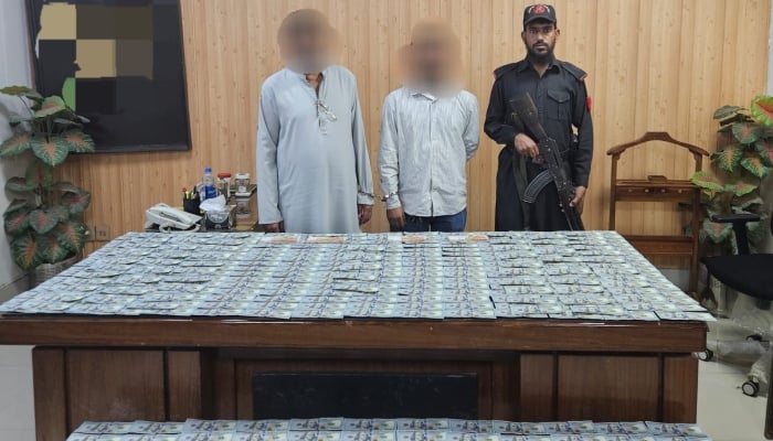 A security official standing guard with two suspects arrested in FIA raid in Karachi on December 5, 2024. —Reporter