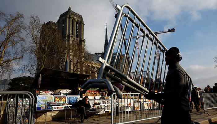 An employee installs barriers to set up a security perimeter in front of the stalls of the booksellers along the banks of the River Seine ahead of the reopening ceremonies of the Notre-Dame de Paris Cathedral in France on December 4, 2024. — Reuters