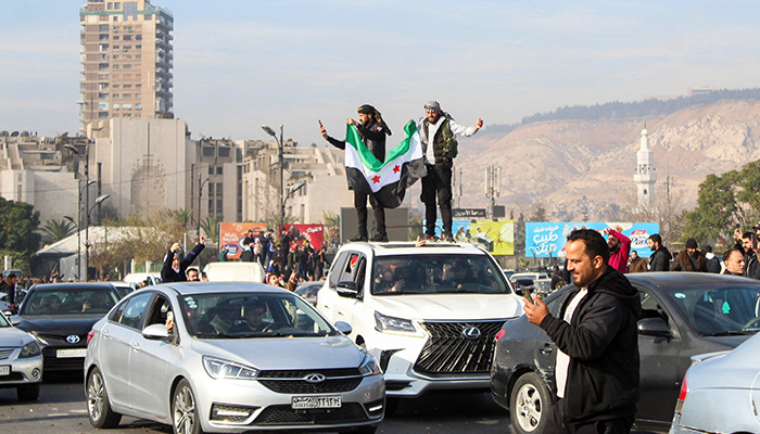 Men hold a Syrian opposition flag on the top of a vehicle as people celebrate after Syrian rebels announced that they have ousted President Bashar al-Assad, in Damascus, Syria December 8, 2024. — Reuters