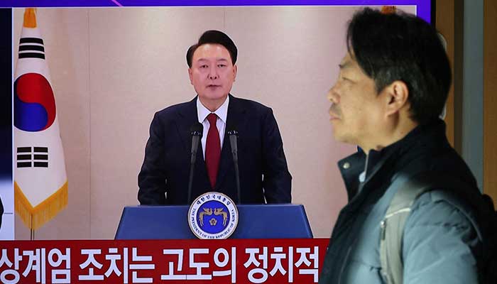 A person stands by a TV screen broadcasting South Korean President Yoon Suk Yeol delivering an address to the nation, at a railway station in Seoul, South Korea on December 12, 2024. — Reuters