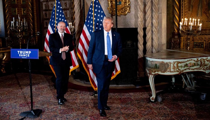 US President-elect Donald Trump, accompanied by Trumps choice for Secretary of Commerce, Cantor Fitzgerald Chairman and CEO Howard Lutnick, takes a question from a reporter during a news conference at Trumps Mar-a-Lago resort on December 16, 2024 in Palm Beach, Florida.— AFP