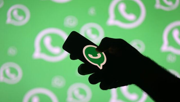 A man poses with a smartphone in front of displayed WhatsApp logo in this illustration September 14, 2017. — Reuters