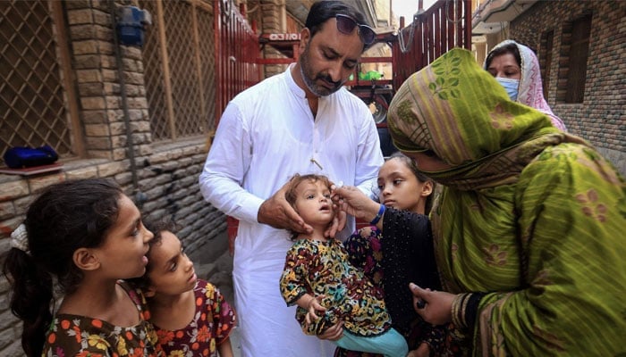 A health worker administers polio drops to a child during a door-to-door vaccination campaign in Peshawar on September 12, 2024. — AFP