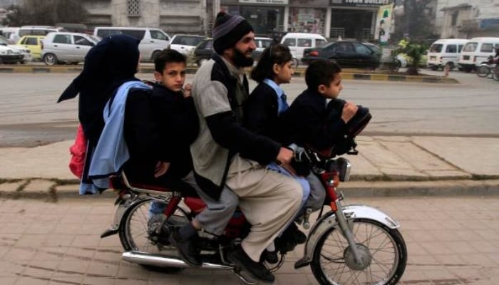 Children ride on a motorcycle with their parent in Rawalpindi. — Reuters/File