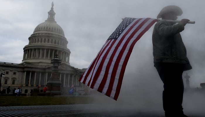 A man holding a flag stands in front of the US Capitol building. —AFP/ File