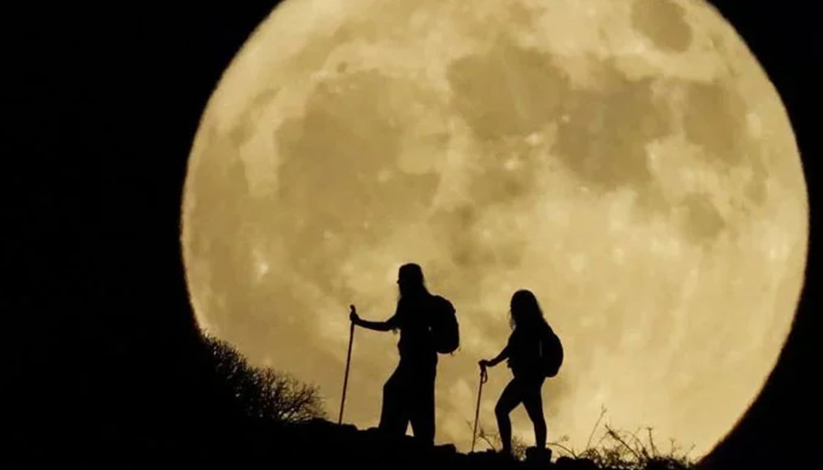 A representational image of a super blue moon behind two women hiking on a hill. — Reuters/File