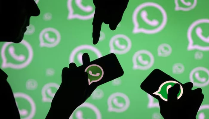 Men pose with smartphones in front of displayed Whatsapp logo in this illustration. — Reuters/File