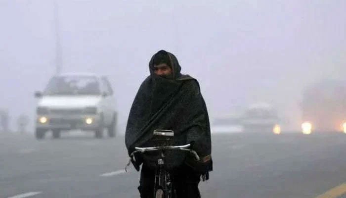 Representational image shows a man wrapped in shawl cycles on a road in cold weather. — AFP/File